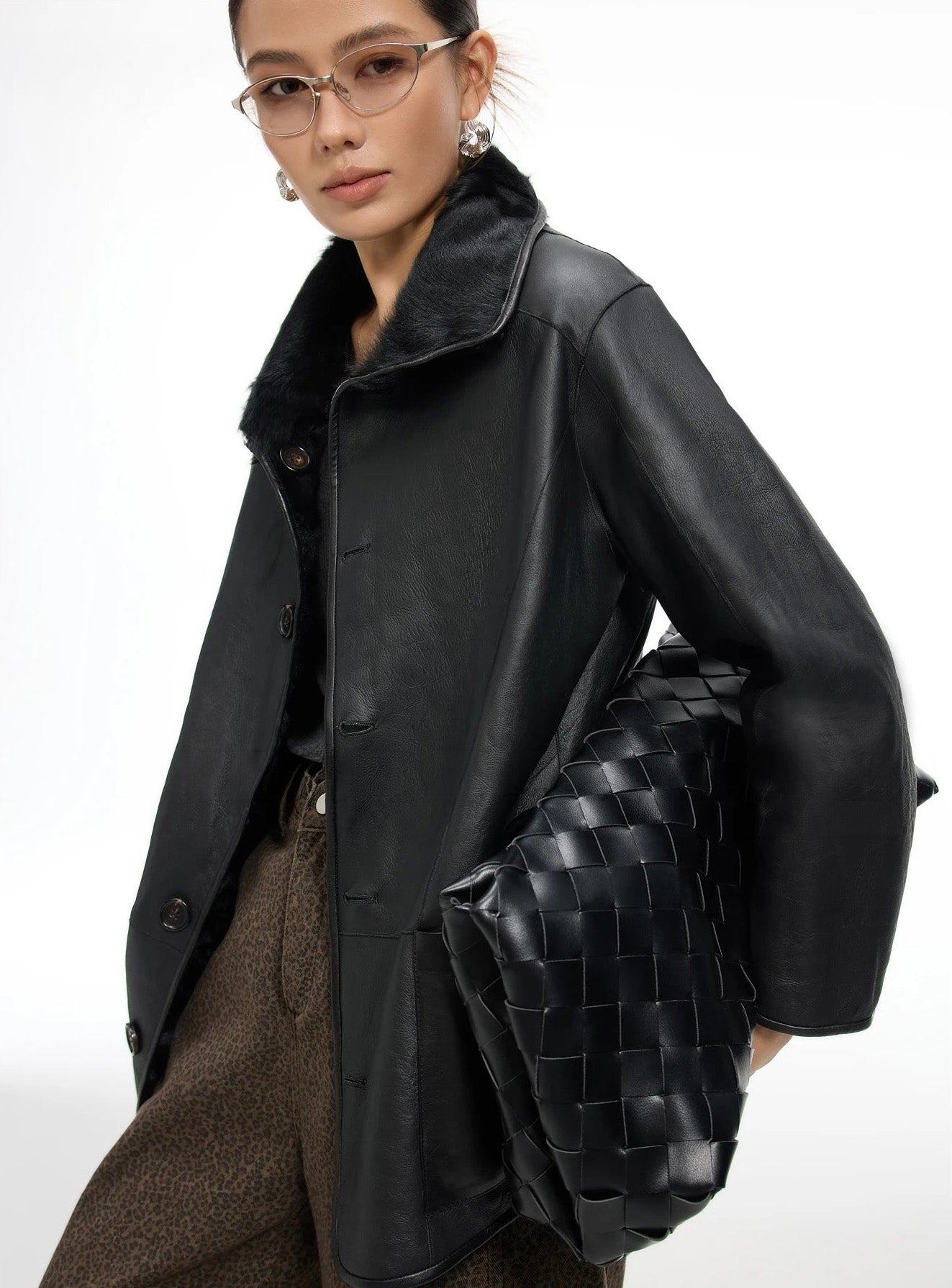 Model standing in the Tusch Swell shearling coat, leather side facing out, holding a woven bag with quiet presence — From Borcelleclothes.