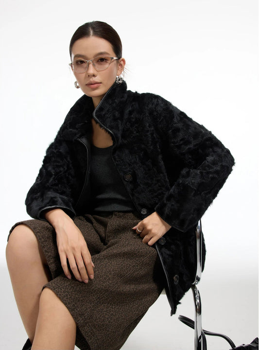 Model sitting with a soft drape of the Tusch Swell shearling coat, fur side out, collar gently framing the neck — From Borcelleclothes.