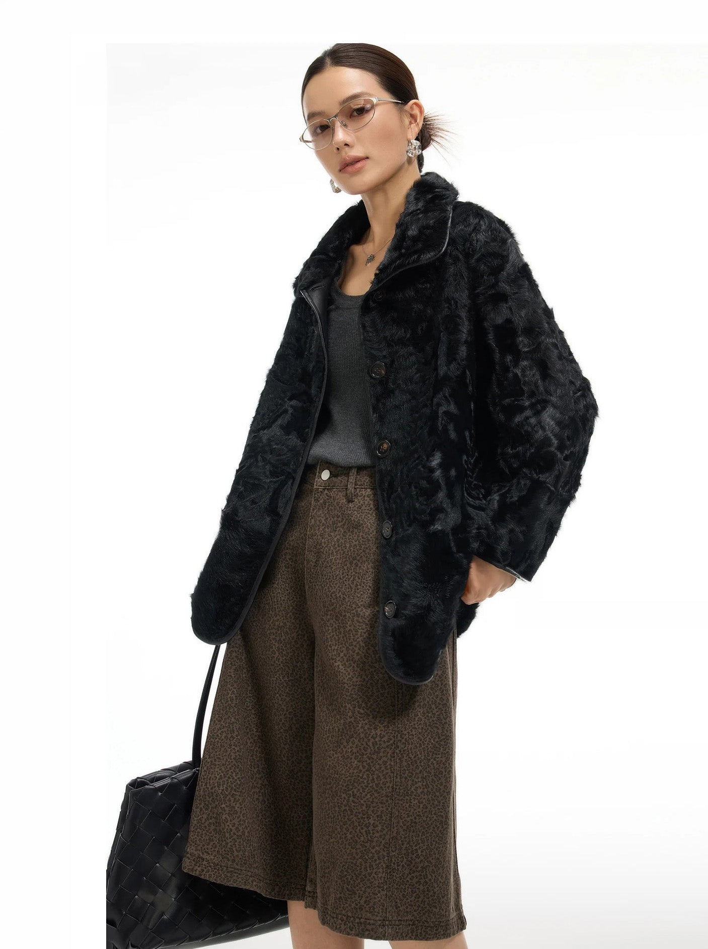 Model slightly turned in the reversible shearling coat, fur surface catching the light along the curved silhouette — From Borcelleclothes.