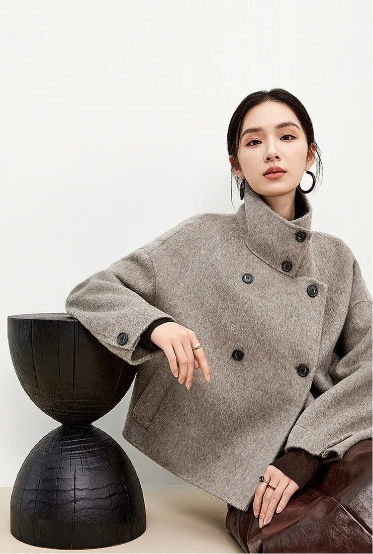 A serene moment: the soft grey wool contrasting with natural wood, reflecting a woman at peace with her surroundings. — From Borcelleclothes.