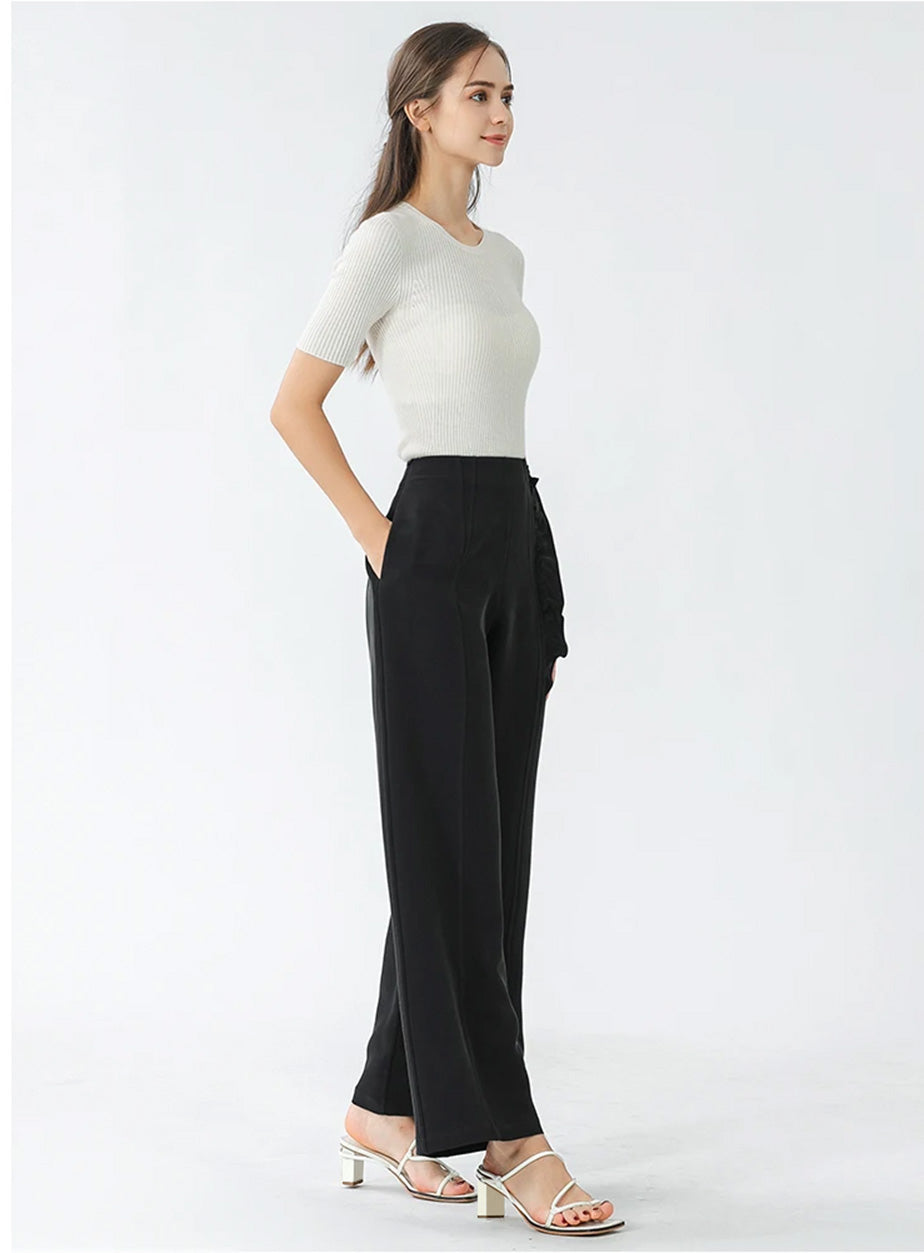 Full-height shot of model with hand in side seam pocket wearing silk wide-leg trousers — From Borcelleclothes.