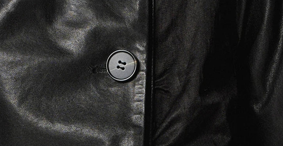 A detail view of the jacket's closure, showing a single high button fastening the wide, matte viscose blend collar into a secure stand. — From Borcelleclothes.