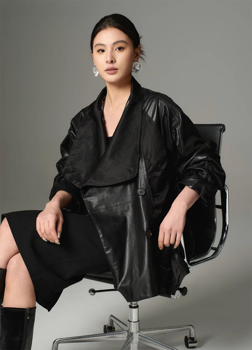 Full-body portrait of a seated model, showcasing the loose-fitting wrap design and the substantial volume of the unfastened Beneath the Mask jacket. — From Borcelleclothes.