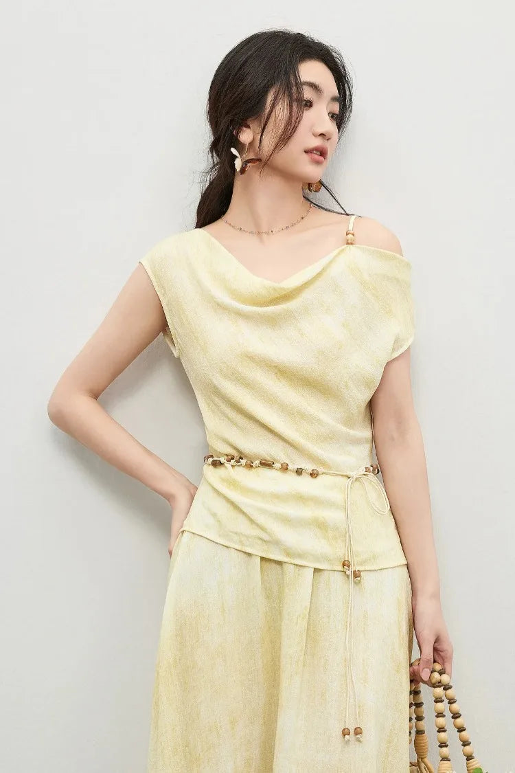 A woman in a golden viscose set looking to the side, emphasizing the sculptural draped waistline — From Borcelleclothes.