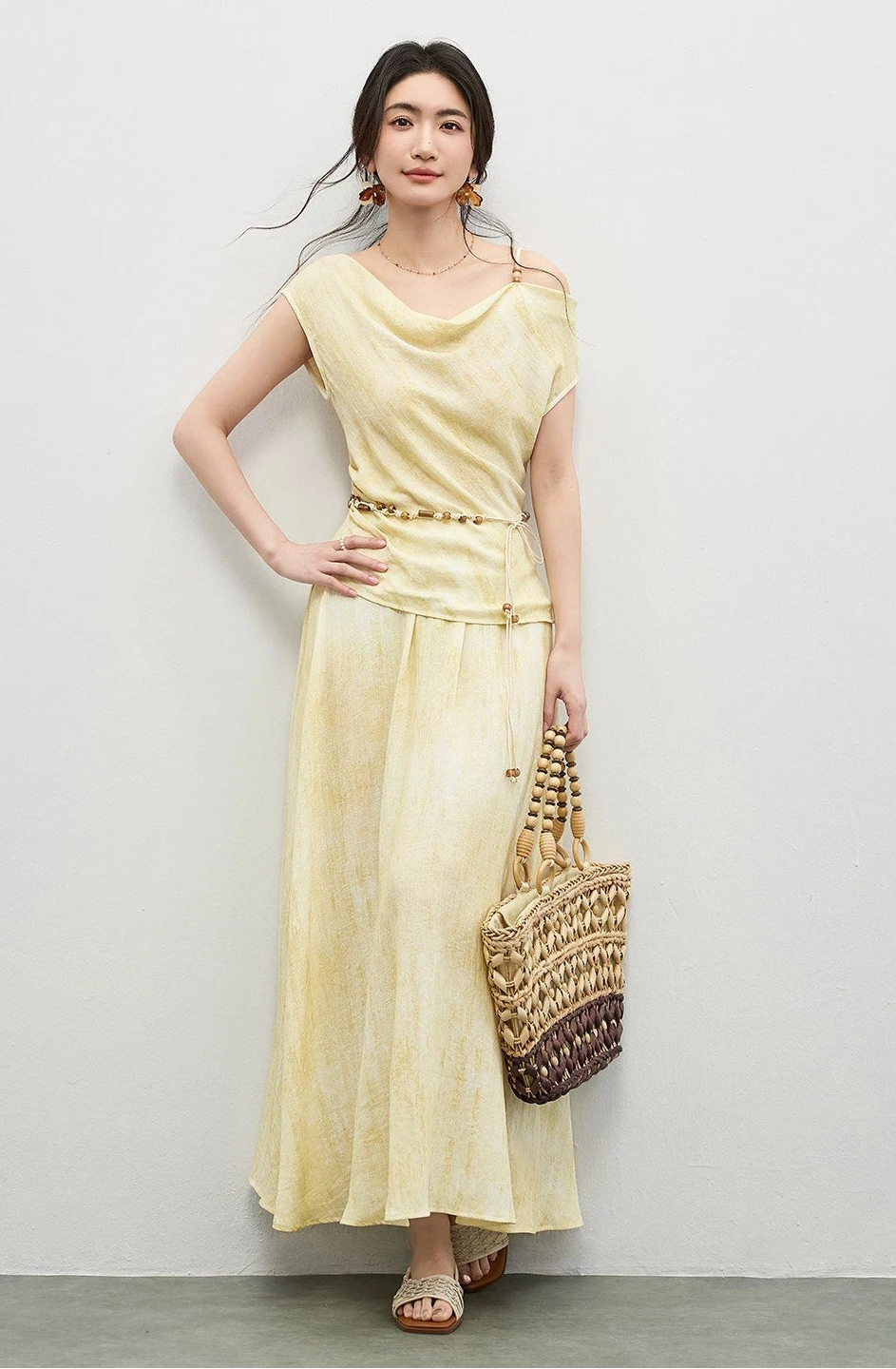 A confident woman posing with her hand on her hip, highlighting the draped silhouette of the golden-olive set — From Borcelleclothes.