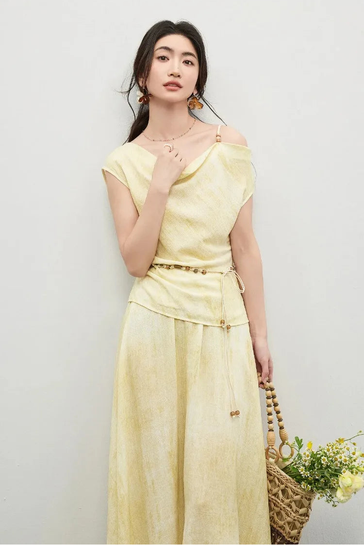 A woman’s hand gently touching the cowl neckline, emphasizing the soft drape and adjustable beaded strap — From Borcelleclothes.
