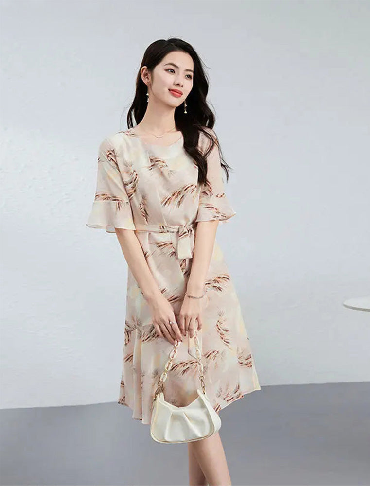 Sophisticated poise of a woman in a "First Light" silk dress, holding a white accessory with both hands to showcase the balanced asymmetrical flow — From Borcelleclothes.