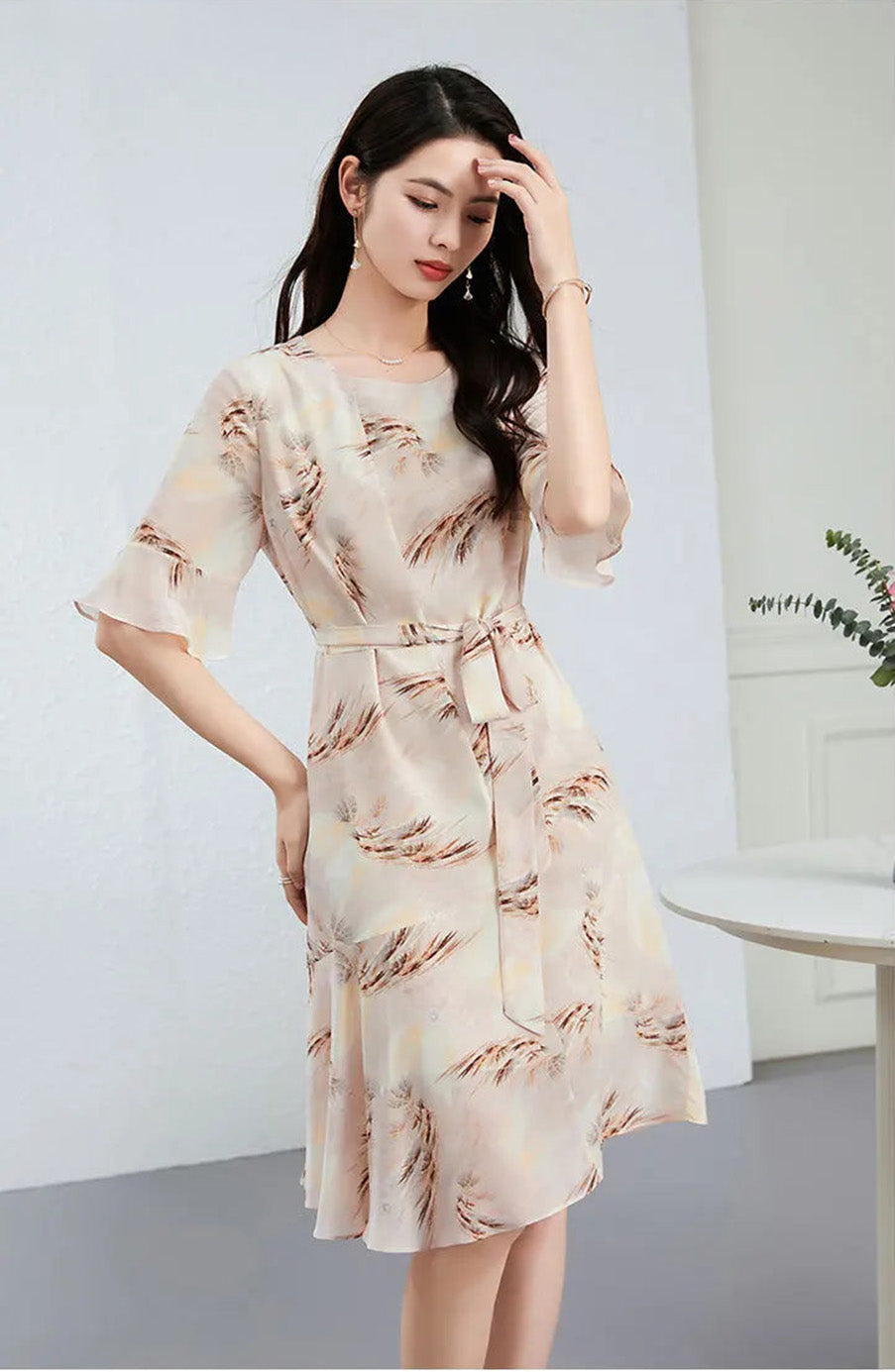 Confident and relaxed, a woman poses in her silk Crepe de Chine dress, showcasing the defined waistline and the effortless grace of the cut — From Borcelleclothes.