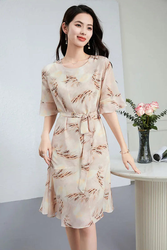 A woman gently feeling the delicate silk texture of her "First Light" dress, highlighting the fluid drape of the Crepe de Chine — From Borcelleclothes.