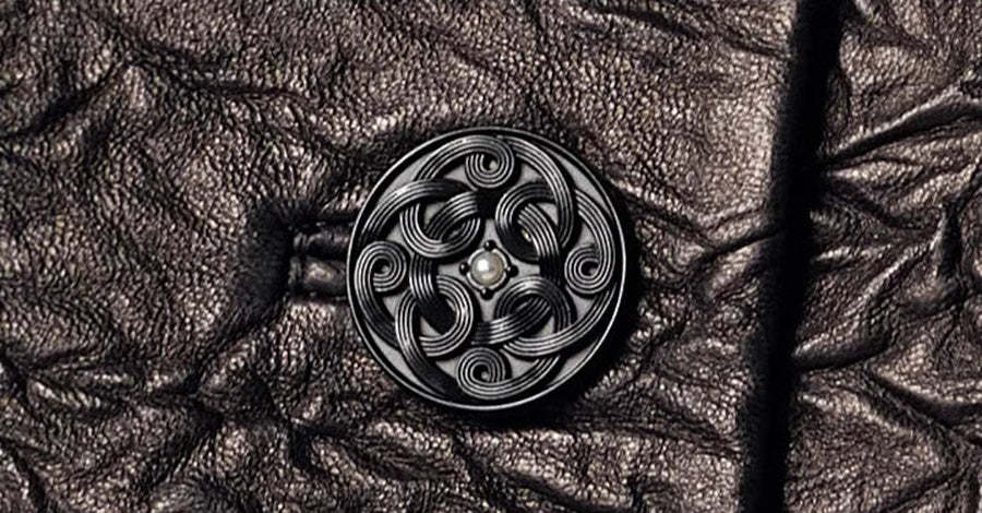 Macro shot of a tonal coiled pattern button with a subtle central pearl accent on sheepskin leather — From Borcelleclothes.