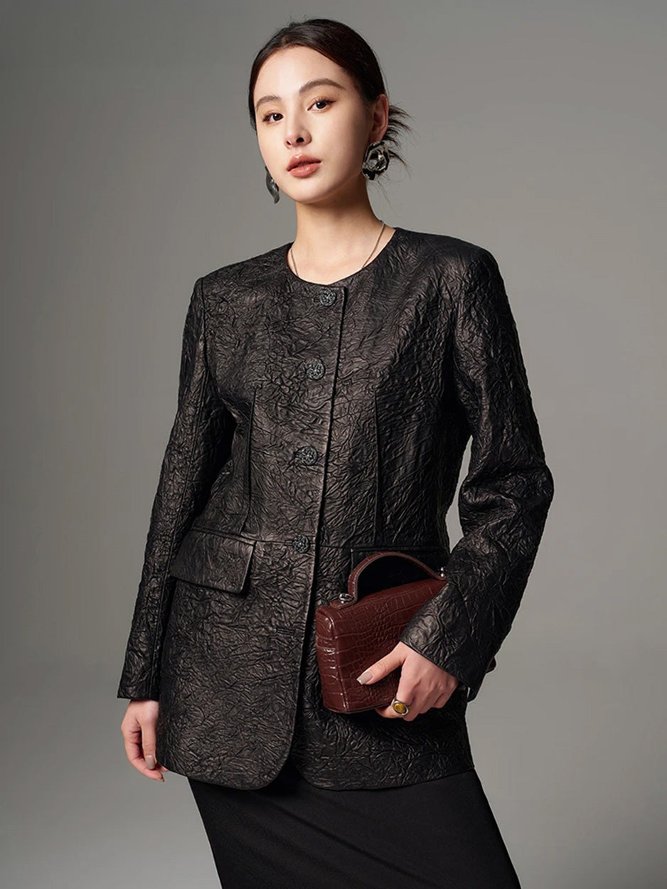 Model posing in a fastened crinkled full-grain sheepskin jacket with a small bag held near the waist — From Borcelleclothes.