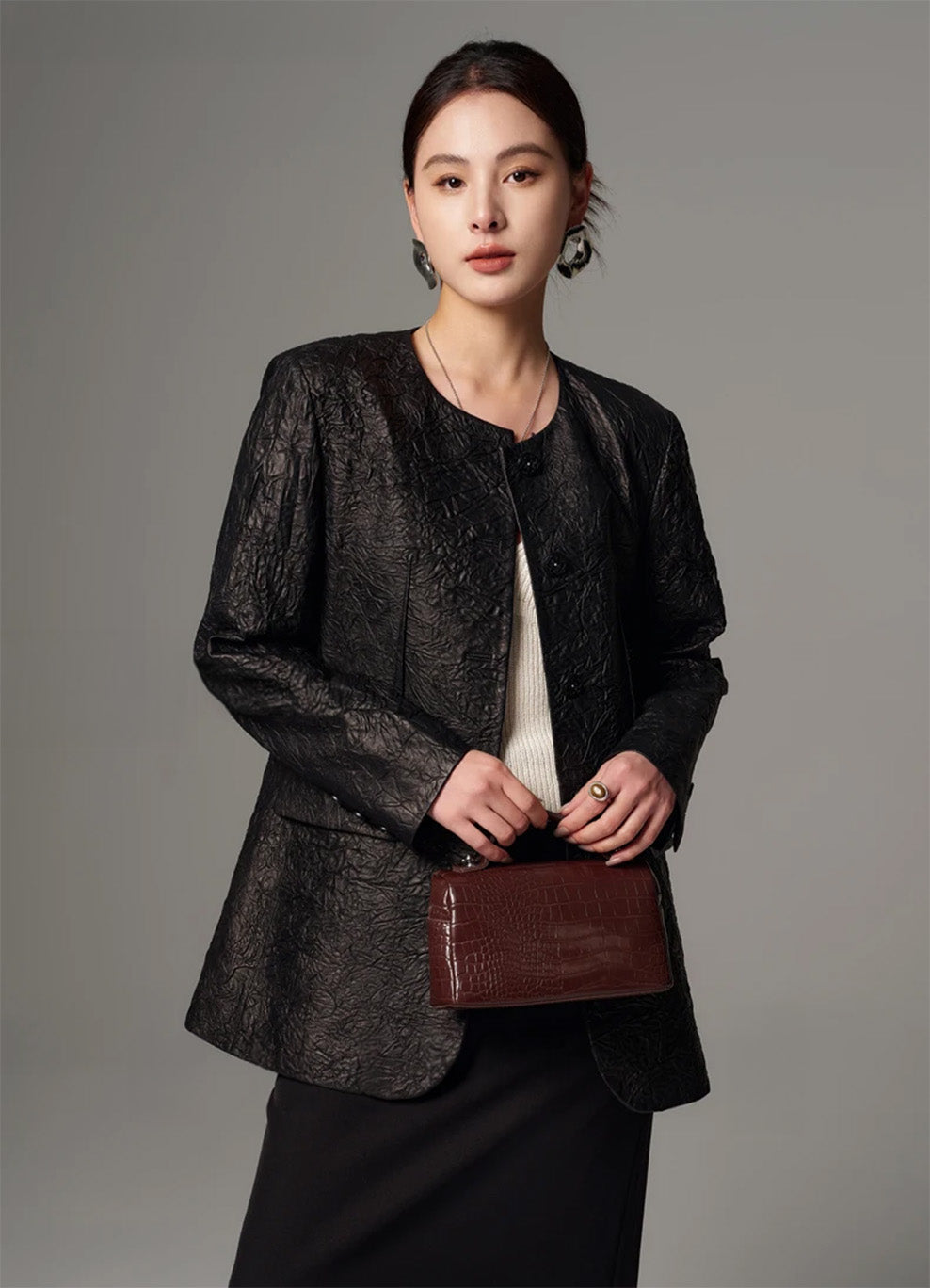 Model styled in a straight silhouette crinkled sheepskin jacket, holding a handbag with both hands — From Borcelleclothes.