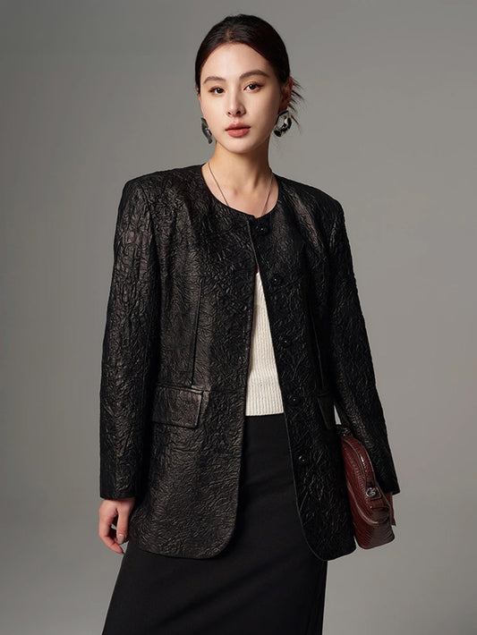 Model wearing a women's crinkled full-grain sheepskin jacket in Crinkled Nocturne, holding a small brown handbag — From Borcelleclothes.