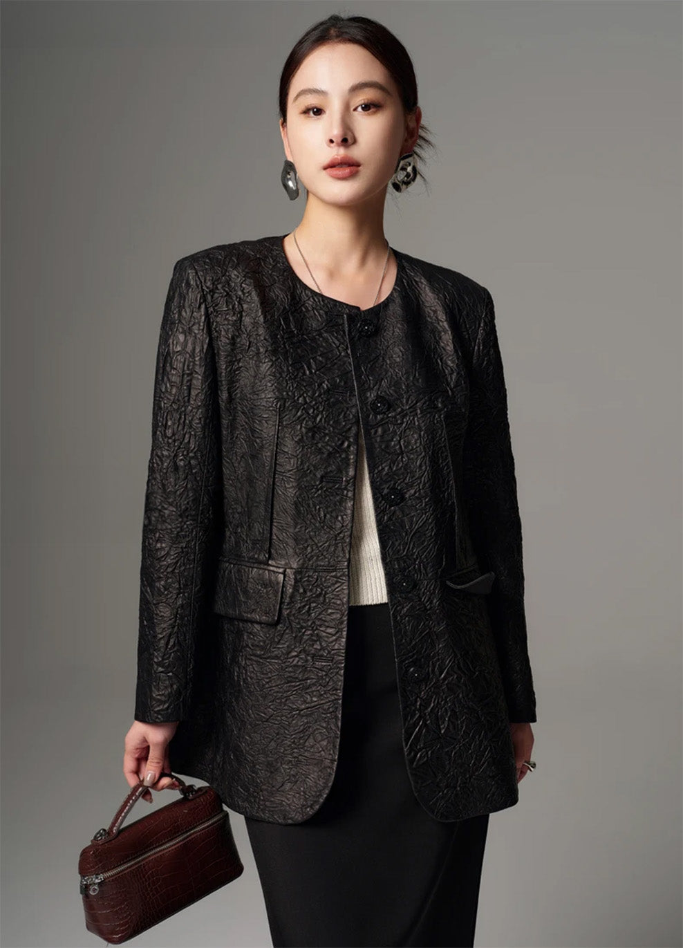 Model wearing an unfastened black crinkled sheepskin jacket, looking directly toward the camera — From Borcelleclothes.