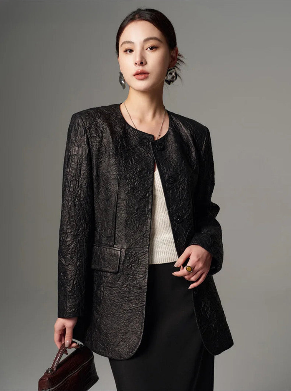 Front view of an unfastened women's crinkled sheepskin jacket worn open by a posing model — From Borcelleclothes.