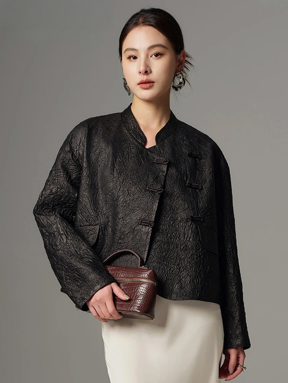 Model wearing a cropped crinkled sheepskin pankou jacket in Frost-Glazed Lava, holding a handbag near the waistline — From Borcelleclothes.