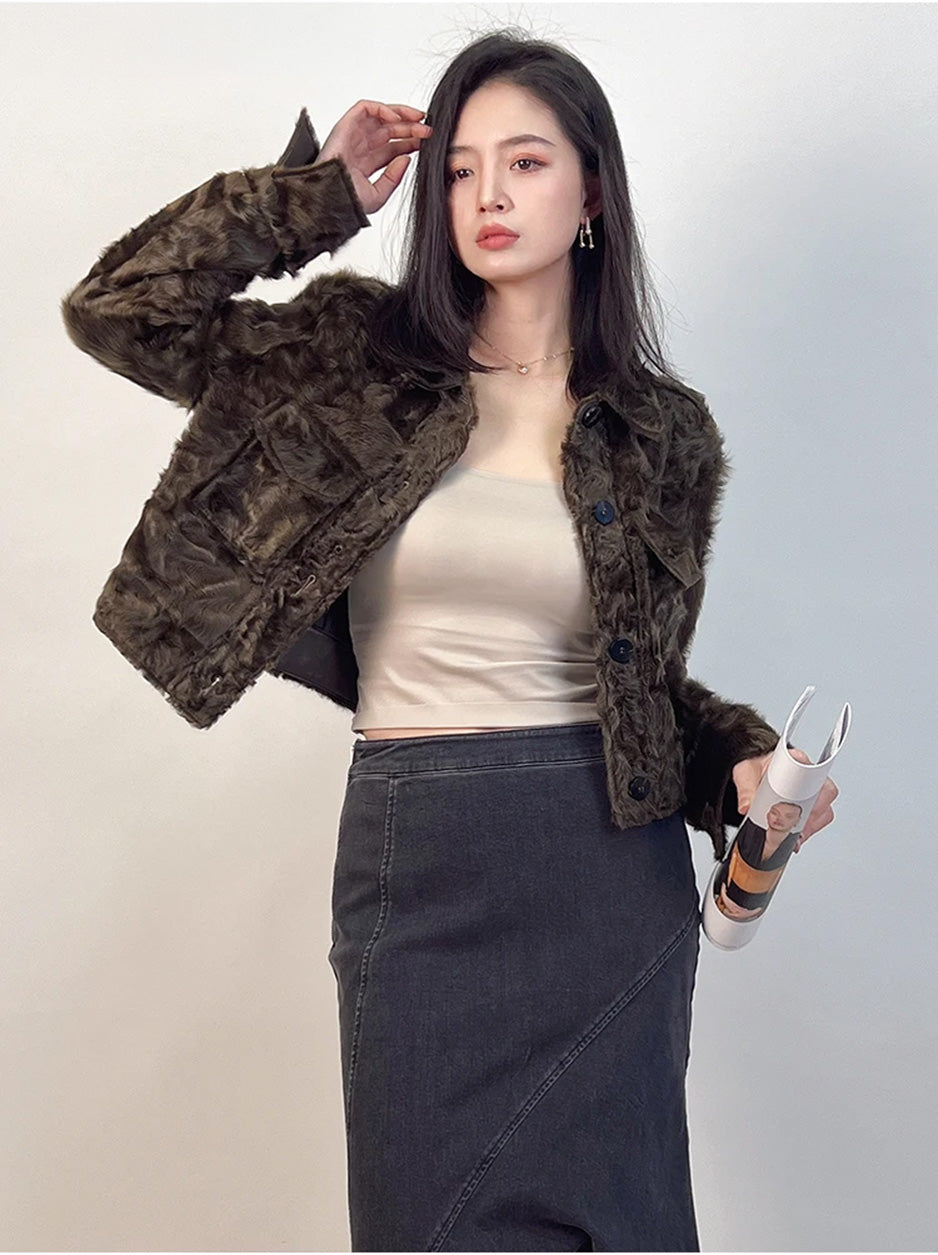 A woman in a cropped Star Anise shearling shirt-jacket, a delicate moment of adjusting her hair that reveals the soft texture of the pointed collar. — From Borcelleclothes.