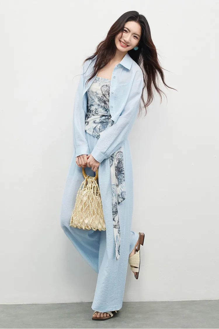 Woman in Lapis Shimmer three-piece set, posing with a lifted foot to showcase the fluid wide-leg trousers. From Borcelleclothes.