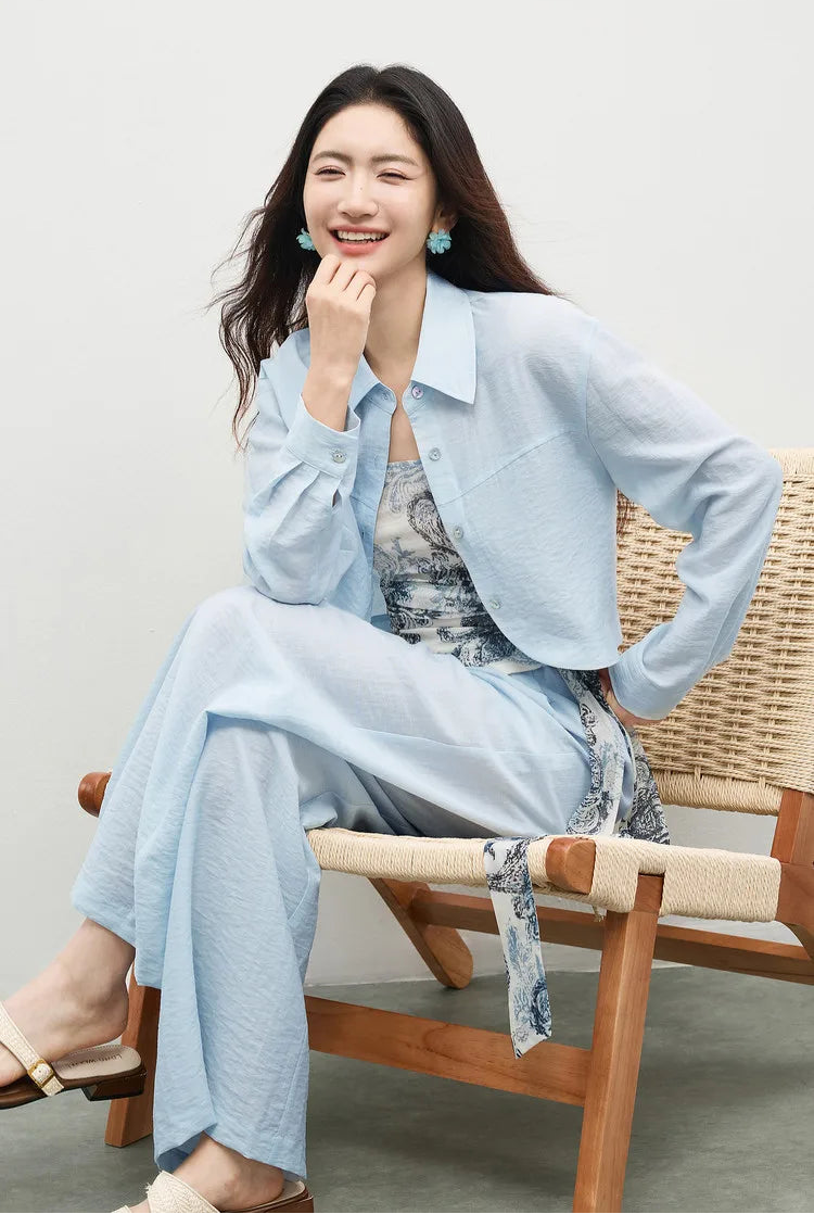 Woman in a thoughtful pose, seated in the Lapis Shimmer three-piece set, highlighting the soft texture of lyocell and linen. From Borcelleclothes.