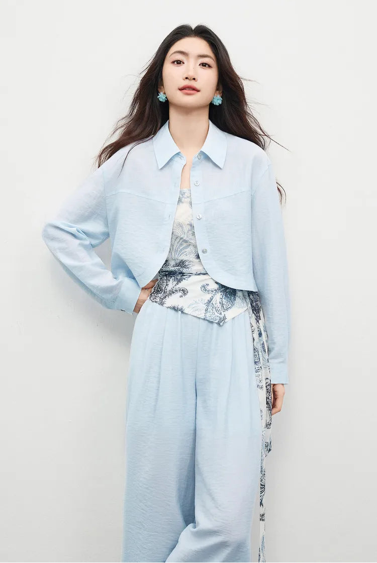 Woman in the Lapis Shimmer three-piece set, hand on waist, highlighting the draped wrap-top silhouette. From Borcelleclothes.