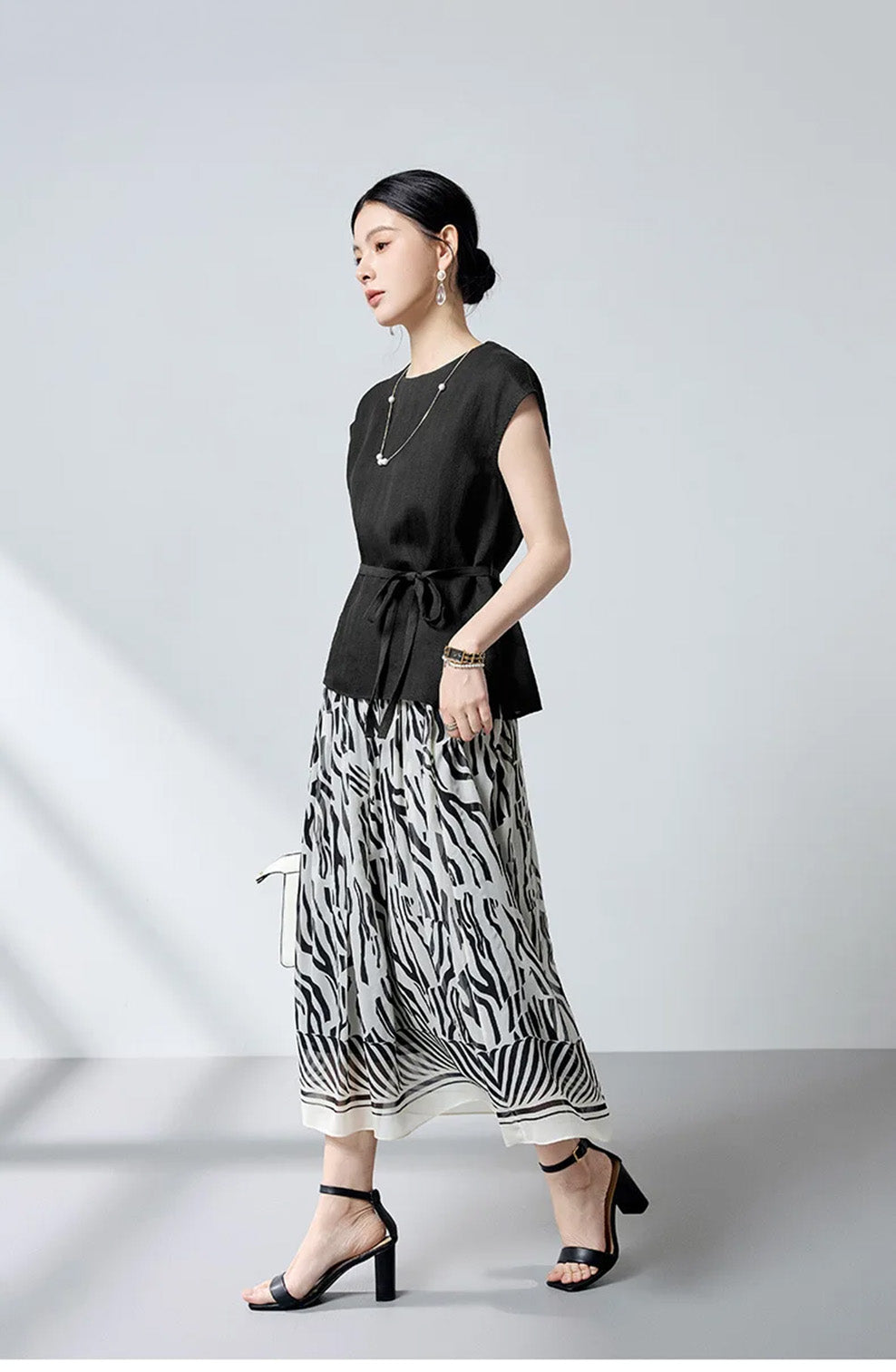 Full-length side view of model walking in the Queen of Spades mulberry silk blouse — From Borcelleclothes.