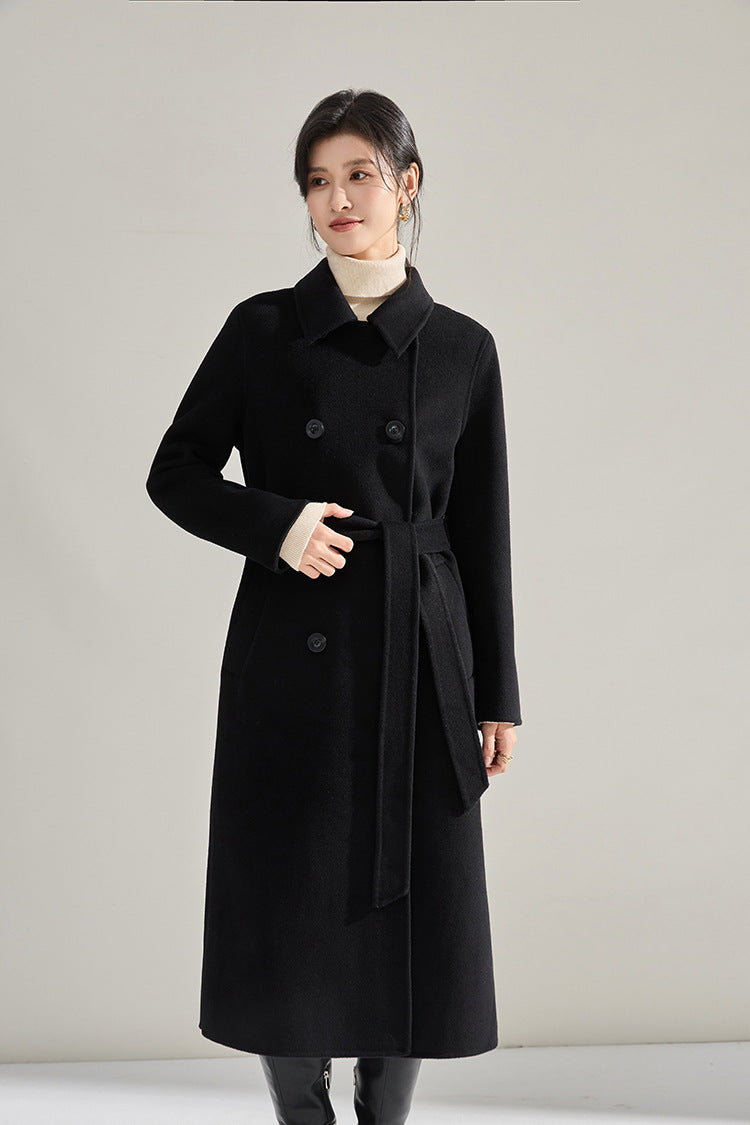 Shadow of a Word black coat, model looking side while adjusting the belt — From Borcelleclothes.