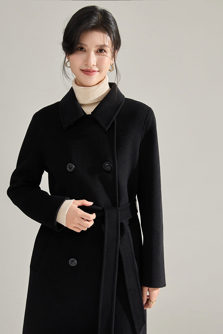Shadow of a Word black coat, model touching the belt at the defined waist — From Borcelleclothes.