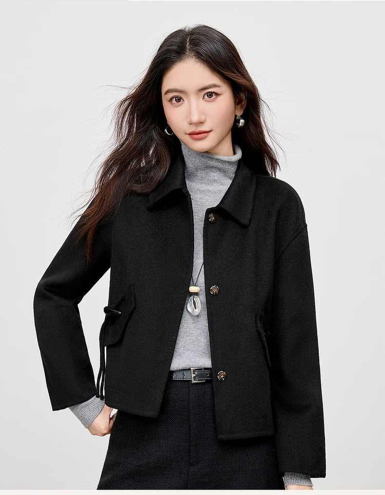 A woman wearing the Black Hellebore wool jacket with her hand on her hip, showcasing the relaxed silhouette — From Borcelleclothes.