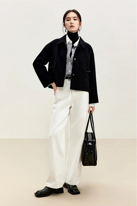 A woman in a Black Hellebore double-sided wool jacket holding an oversized black leather bag — From Borcelleclothes.