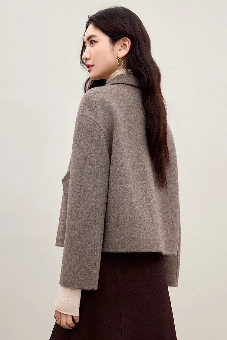 A back view of a woman in the Lost Summit wool jacket, showing the impeccable drape of the 850g/m² wool — From Borcelleclothes.