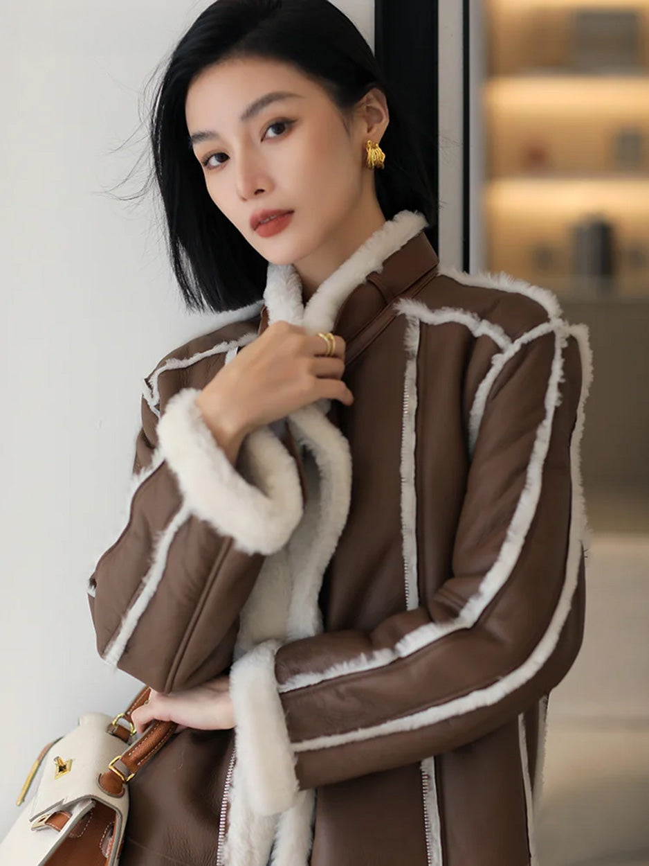 Model touching the collar of the Drambuie Cocktail shearling coat, bag held in one hand — From Borcelleclothes.