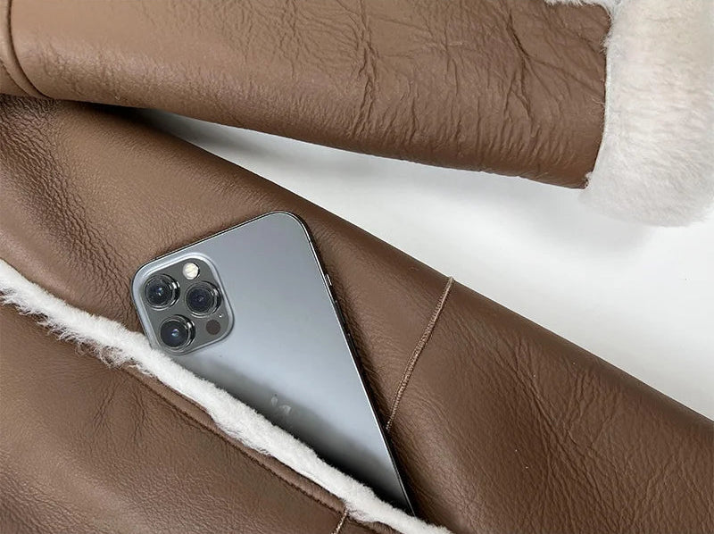 Phone tucked into the pocket of the Drambuie Cocktail shearling coat — From Borcelleclothes.
