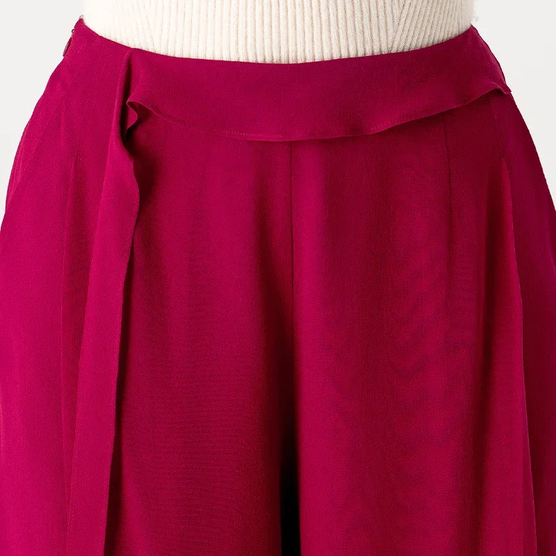 Detailed front view of the high waist with an asymmetrical draped overlay pivoting into a vertical cascade — From Borcelleclothes.