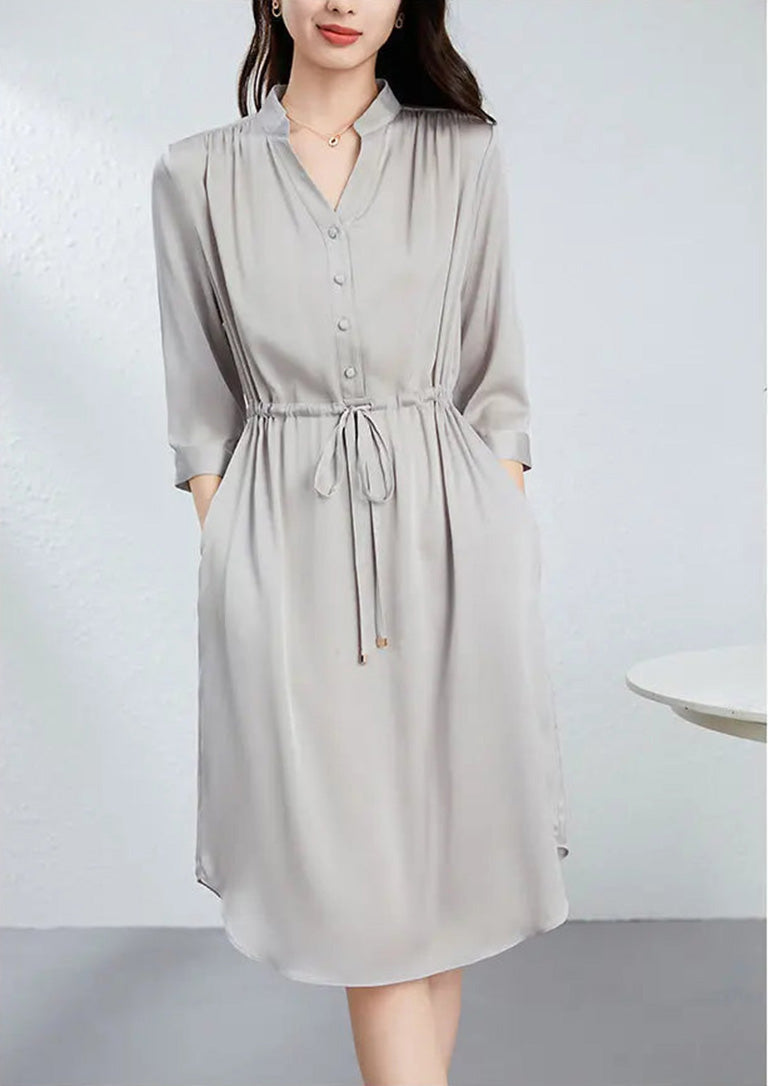 A woman standing with crossed legs and hands in pockets, showing the sophisticated midi length and relaxed fit of the dress. — From Borcelleclothes.