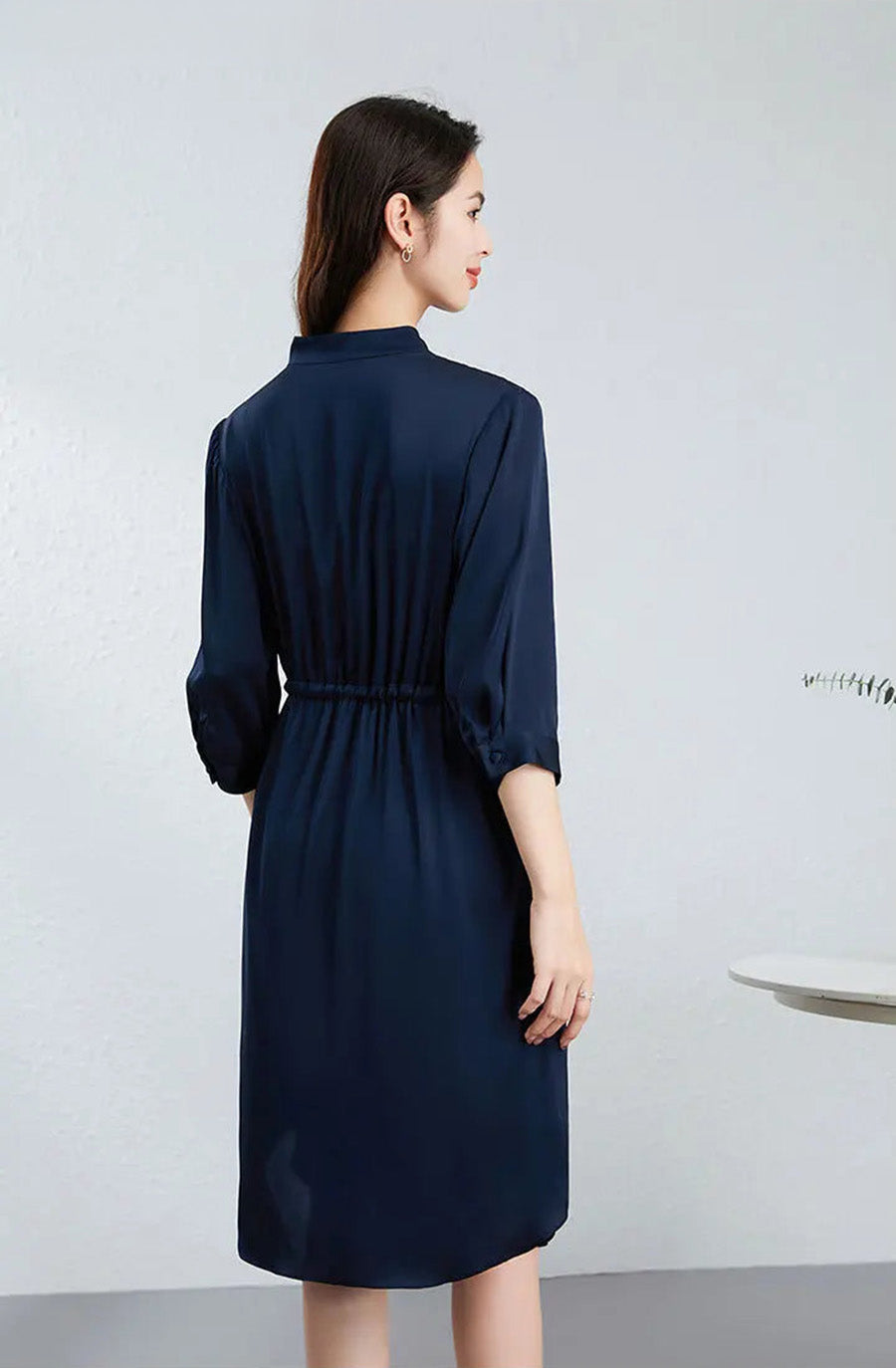 Rear view of a woman in a loose-fitting silk dress, showing the fluid drape and midi length of the Monticola Solitarius edition. — From Borcelleclothes.