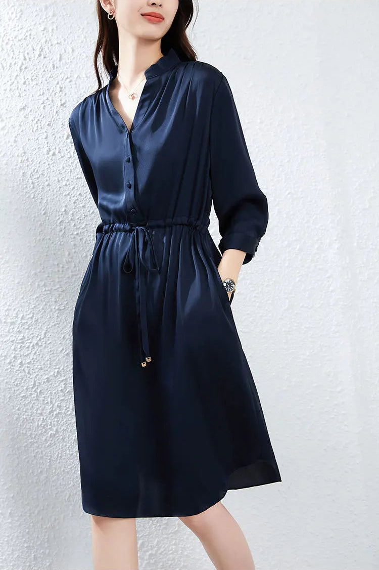 A woman poses gracefully with her hands in the side seam pockets of her silk midi dress, showcasing a relaxed yet elegant silhouette. — From Borcelleclothes.