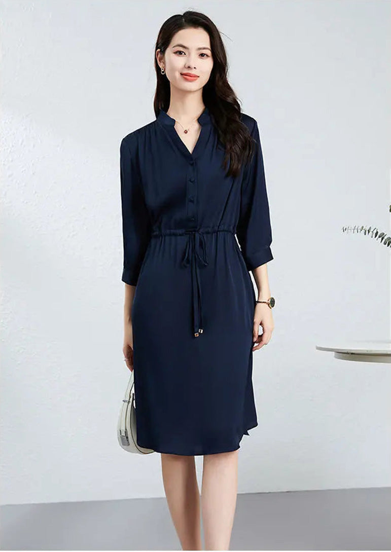 A woman in a dark blue double georgette silk dress carries a white handbag, highlighting the contrast between the fluid silk and structured accessories. — From Borcelleclothes.