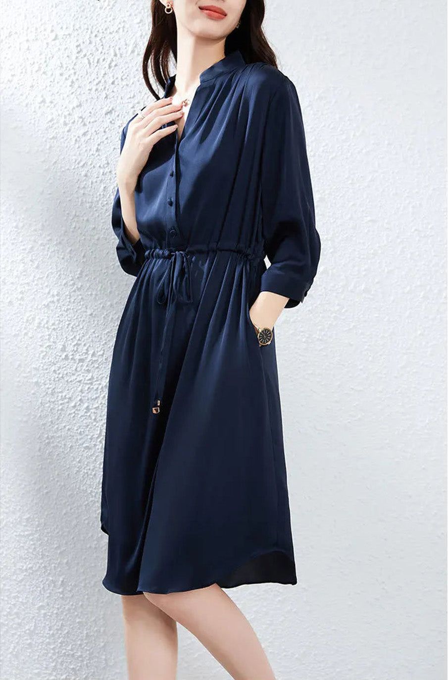 Woman resting her hand near the neckline, emphasizing the architectural clarity of the stand-up collar. — From Borcelleclothes.