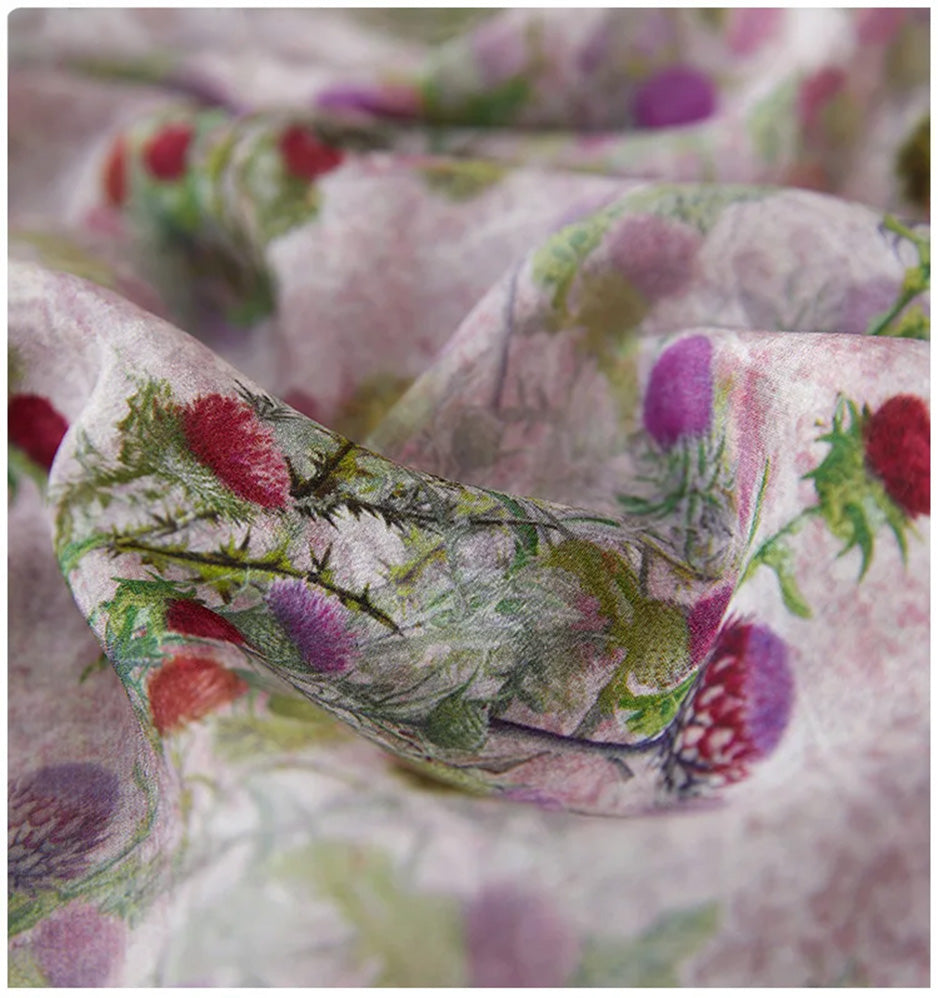 A close-up of the 100% Mulberry silk crepe de chine in a wave-like fold, revealing the matte grain and the delicate thistle print in a misty morning hue. — From Borcelleclothes.