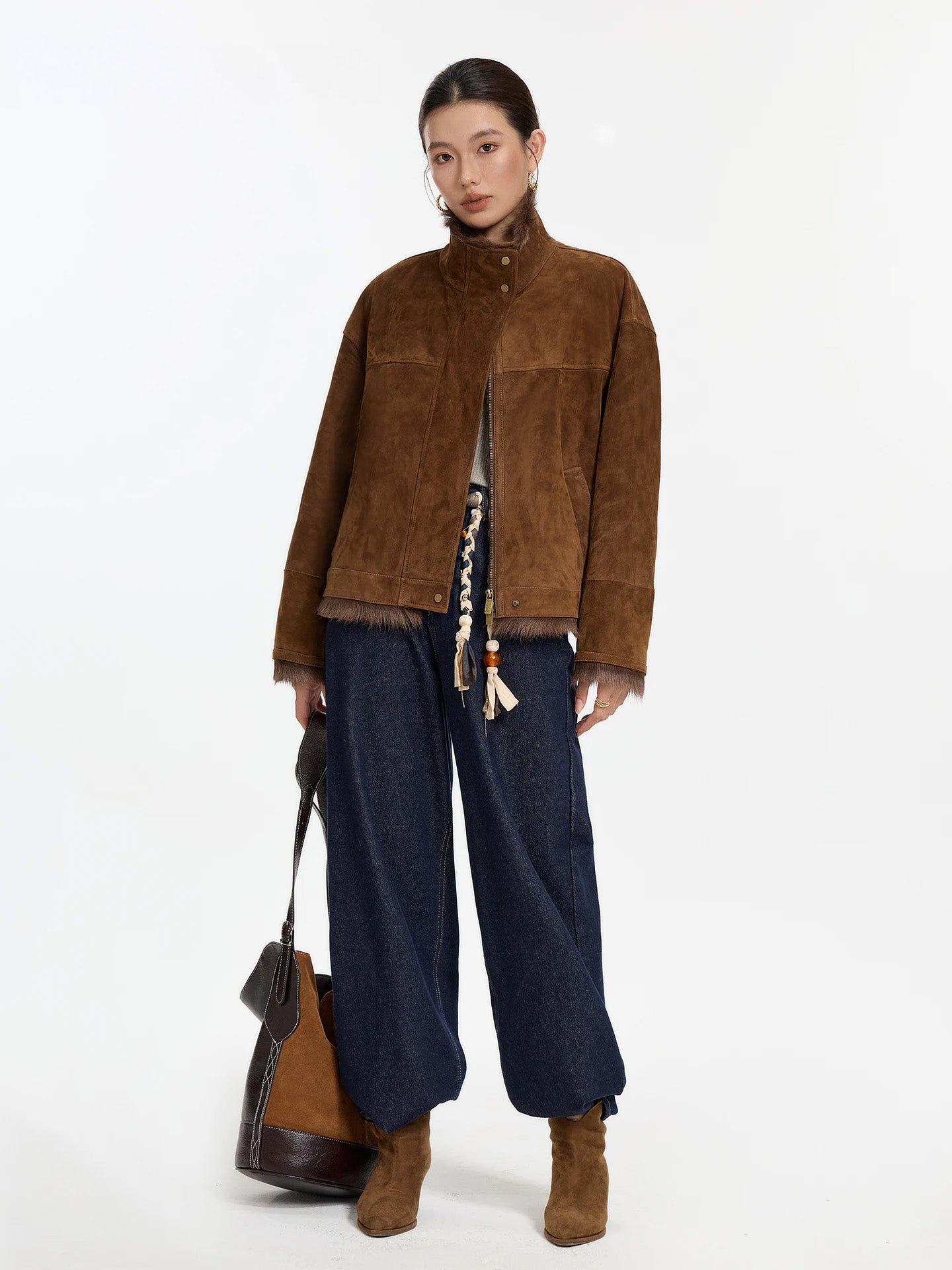 Model holding oversized bag while wearing goatskin jacket in Dark Rum — From Borcelleclothes.