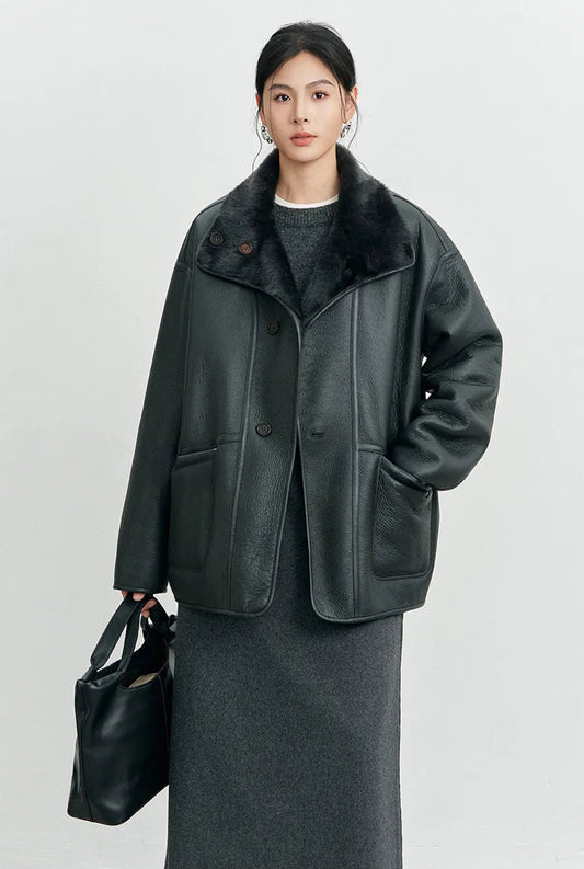 Woman wearing dropped-shoulder reversible shearling jacket in Dim Underdusk, hand in pocket, leather side — From Borcelleclothes.