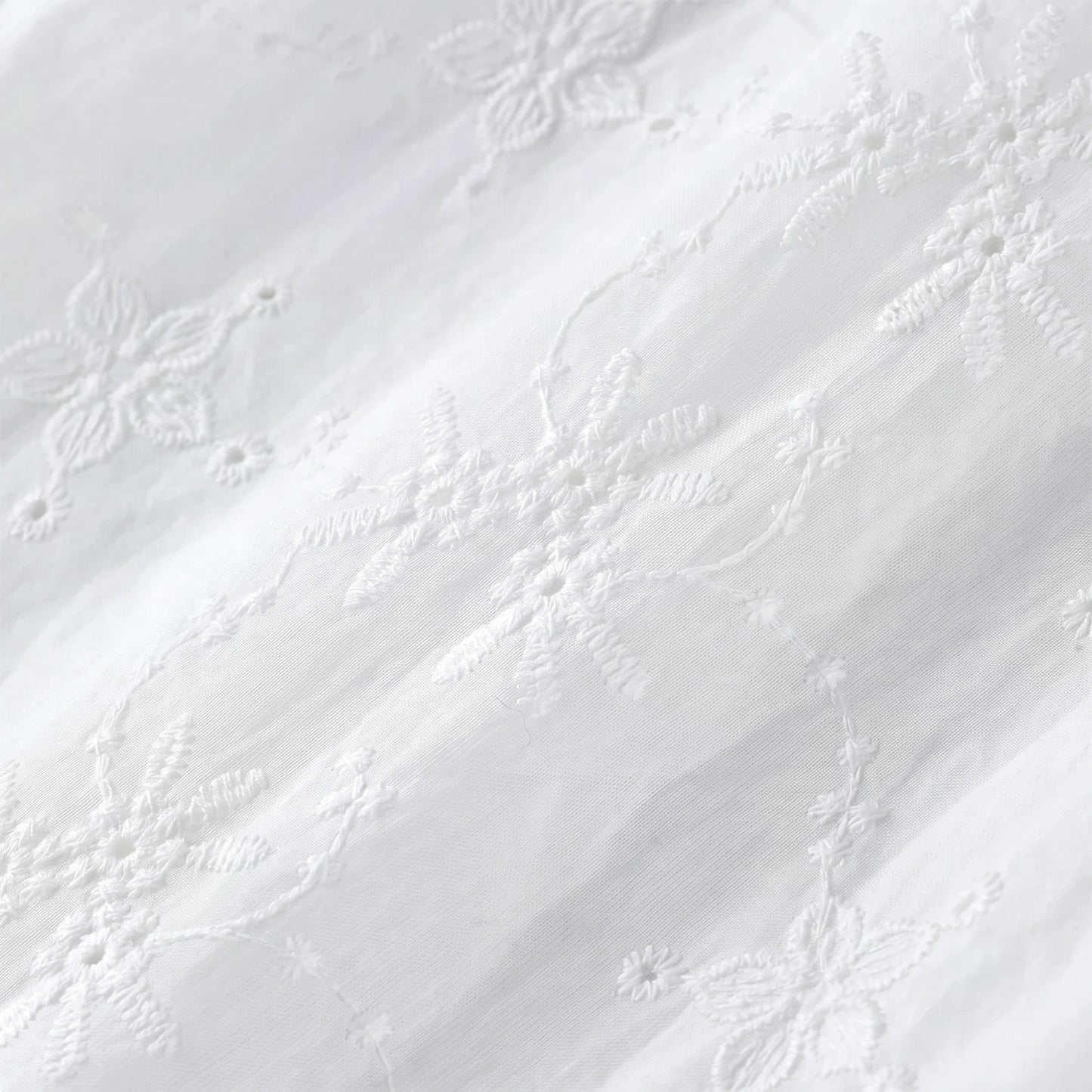 Close-up macro shot of the premium 100% matte cotton fabric revealing the intricate Madeira floral eyelet embroidery — From Borcelleclothes.