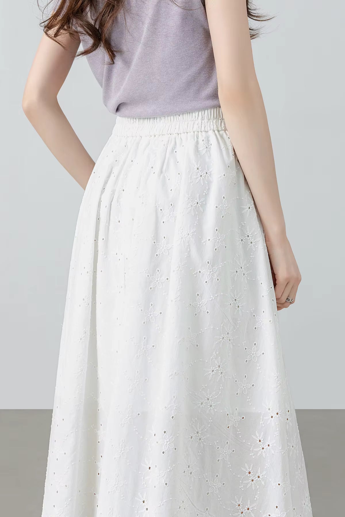 Back view of a model wearing the white embroidered cotton skirt, showcasing the clean-finished back layout — From Borcelleclothes.
