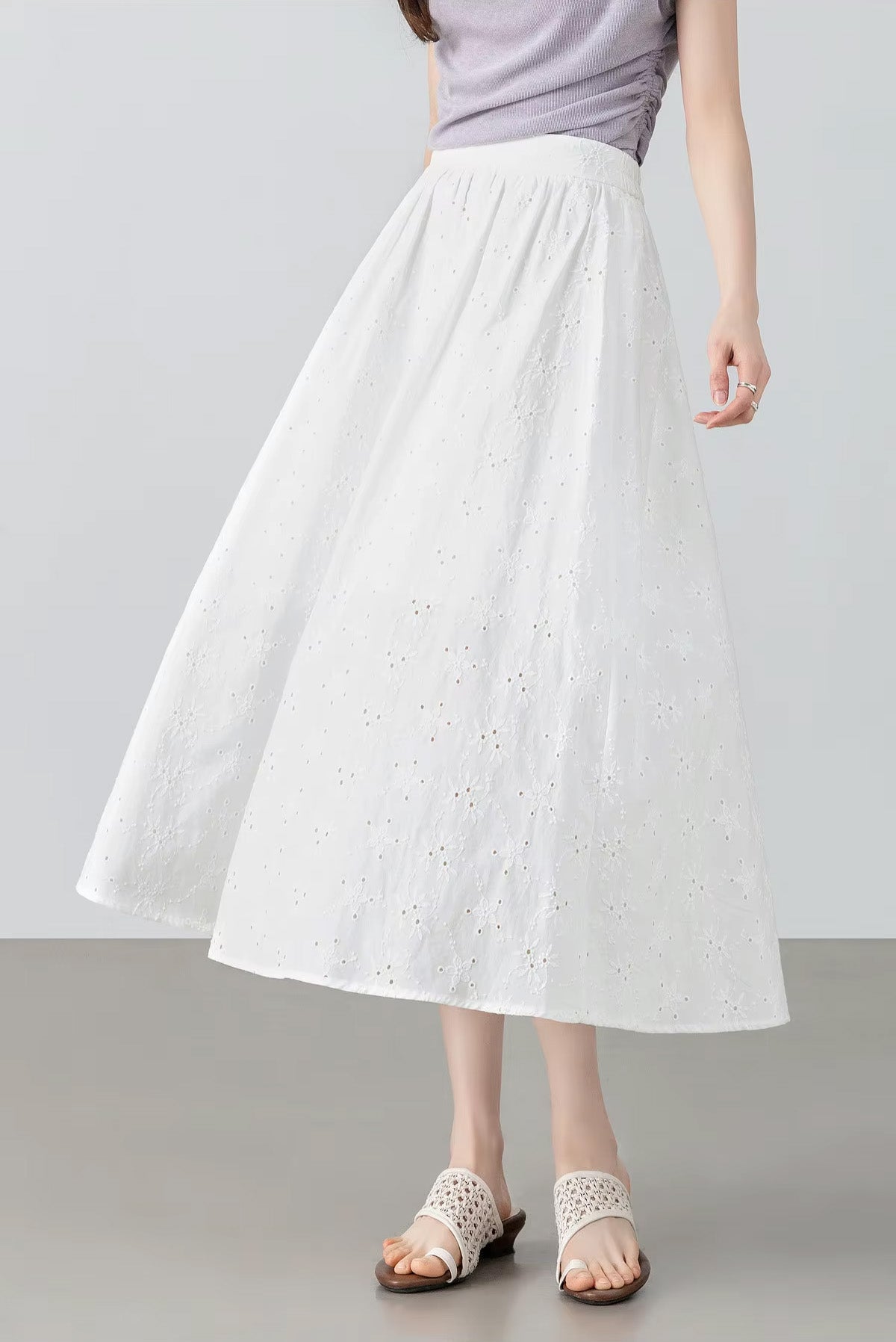 Action shot of a model swirling in the white eyelet cotton skirt, beautifully capturing the wide 2.5-meter hem circumference and volume — From Borcelleclothes.