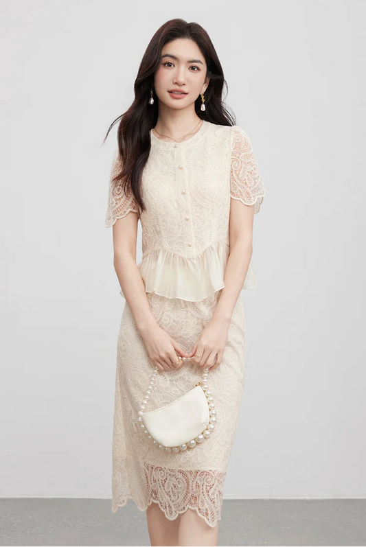 A woman in a lace-embroidered set holding a small pearl bead bag, a delicate accessory reflecting the five pearl buttons of the bodice. — From Borcelleclothes.