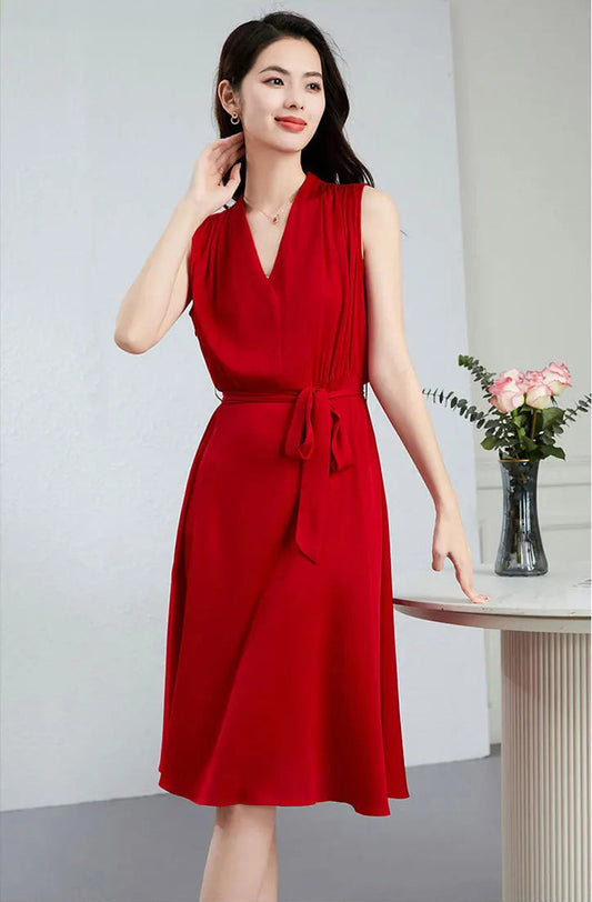 A woman in a red silk georgette dress gently touches her neck, highlighting the elegant continuous-cut collar — From Borcelleclothes.