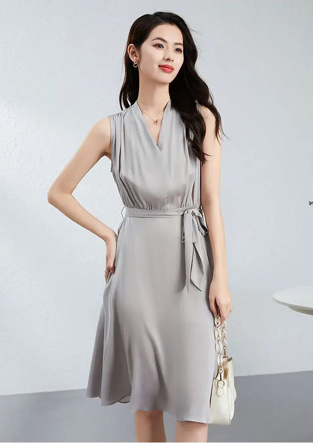 A woman poses in a silk wrap-style dress with a white accessory, emphasizing the self-tie belt and knit loops — From Borcelleclothes.