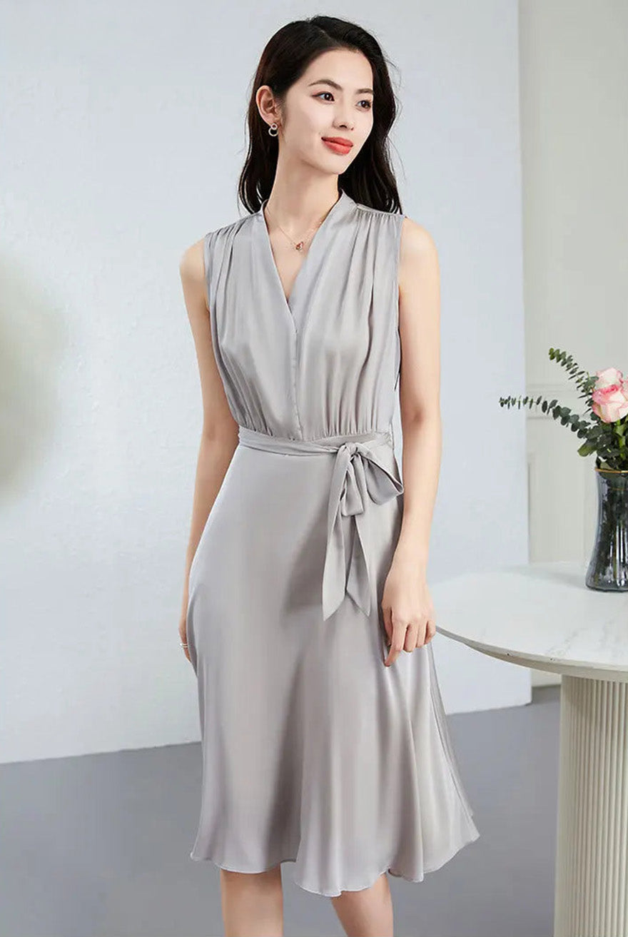 A woman in a Taste of Win silk dress stands at an angle, highlighting the sophisticated flared sleeveless silhouette — From Borcelleclothes.