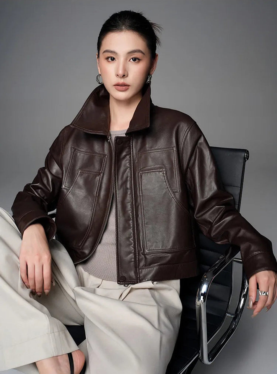 Model seated in an armchair wearing the boxy cropped sheepskin jacket in Rich Juniper — From Borcelleclothes.