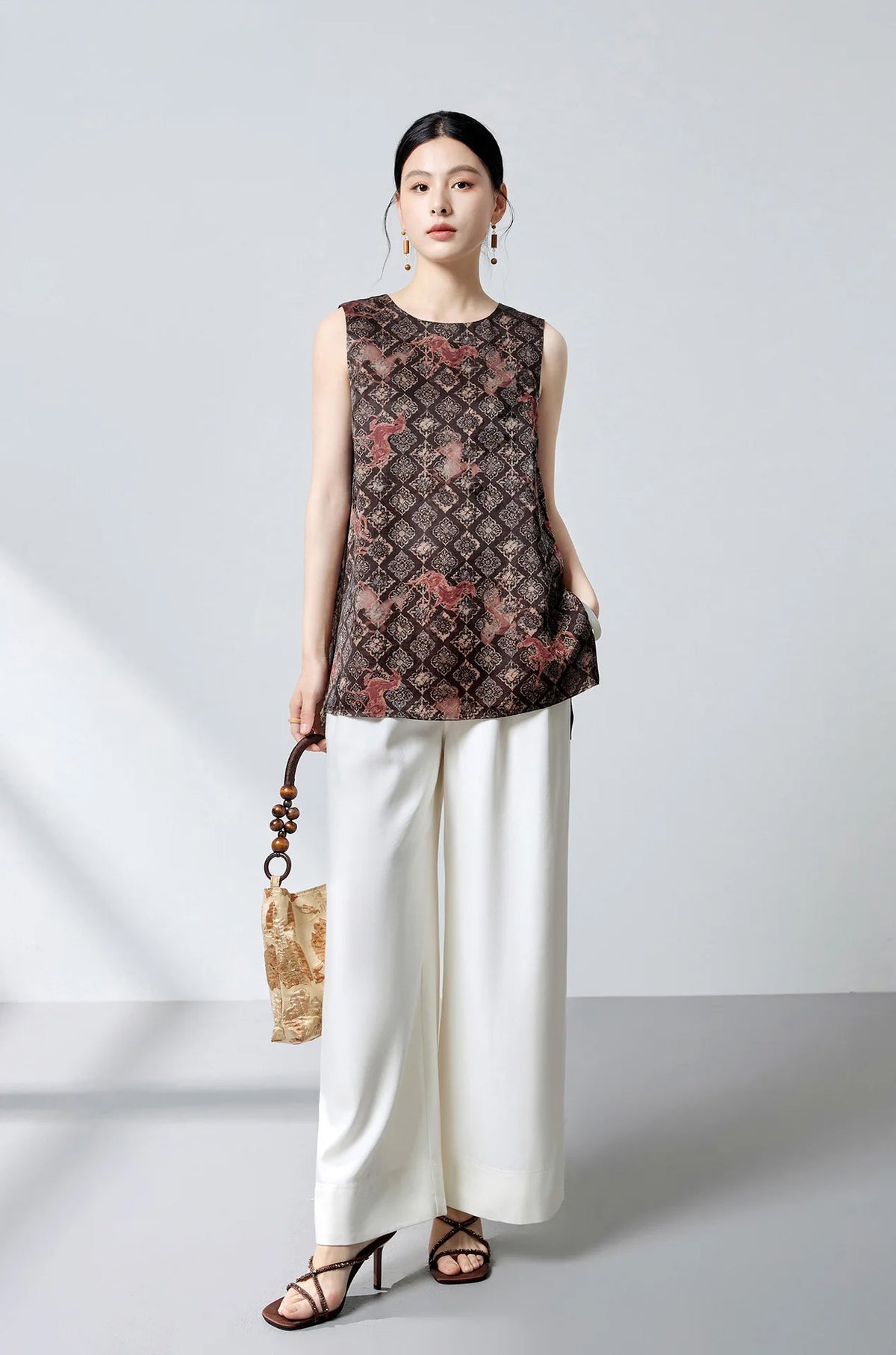 Model styled in the espresso Xiangyunsha silk top holding an elegant leather handbag — From Borcelleclothes.